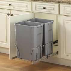 a kitchen cabinet with two trash cans in it