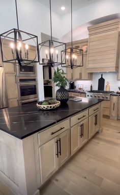 a large kitchen with an island in the middle and lights hanging from it's ceiling