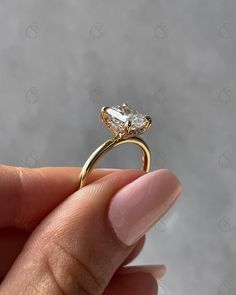 a hand holding a gold ring with a pear shaped diamond in it's center