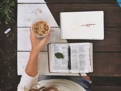 a person sitting at a table with an open book and cup of coffee