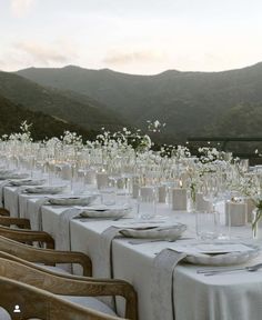 a long table is set with white flowers and place settings