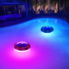 an illuminated pool at night with two lights on the bottom and one in the middle