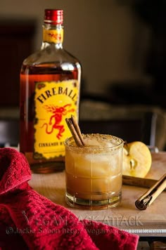 a bottle of fireball next to a glass filled with an alcoholic drink and cinnamon sticks