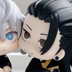 two anime figurines are sitting next to each other, one is kissing the other