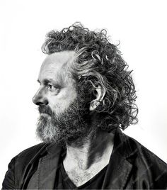 a black and white photo of a man with curly hair looking off to the side