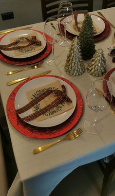 a table set for christmas dinner with place settings and napkins on the plate holders