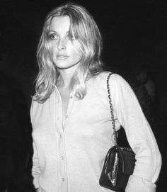 a black and white photo of a woman holding a handbag in her right hand