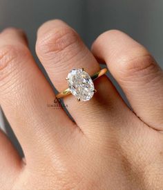 a woman's hand with a diamond ring on top of her finger, showing the center stone