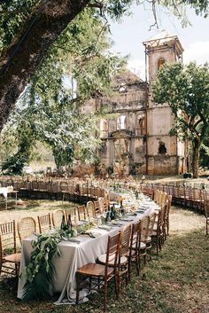 an outdoor wedding with tables and chairs set up in front of the building, surrounded by greenery