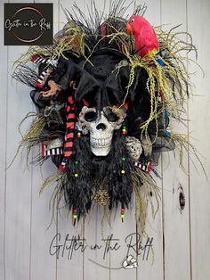 a skull mask with feathers on it is hanging on a white wooden wall next to a red bird