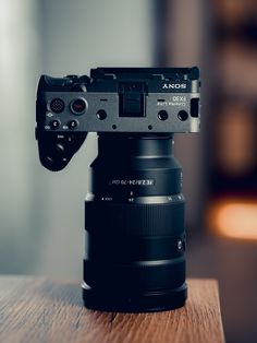 a camera on top of a wooden table with the lens attached to it's body