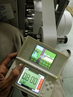 a person holding an electronic device in front of a machine with the screen on it