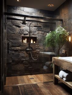 a bathroom with wood flooring and stone walls, along with a glass shower door