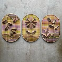 three wooden plaques with flowers and leaves on them are hanging on a wall in the shape of circles