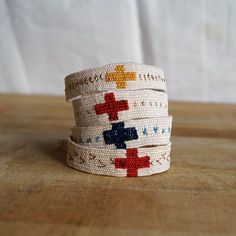 four bracelets with crosses on them sitting on a wooden counter top next to a white wall