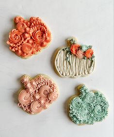 three decorated cookies sitting next to each other on a white counter top with swirly icing