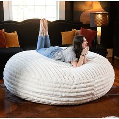 a woman laying on top of a large white bean bag chair in a living room