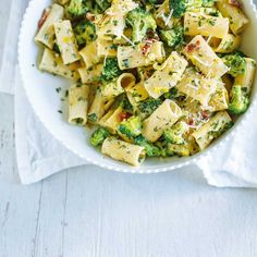 a bowl filled with pasta and broccoli on top of a white tablecloth