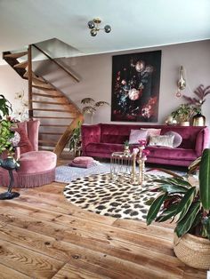 a living room filled with pink furniture and lots of plants on top of it's hard wood flooring