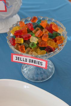 there is a bowl full of gummy bears on the table next to plates and napkins