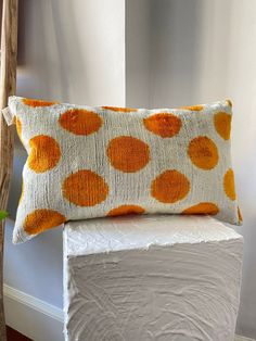 an orange and white pillow sitting on top of a wooden block