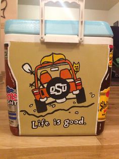 a cooler sitting on top of a wooden floor next to a bottle of ketchup