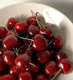 a white bowl filled with cherries on top of a table