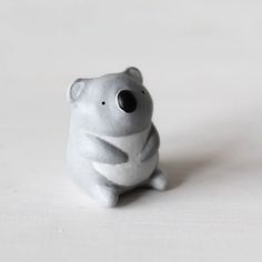 a white ceramic figurine of a koala sitting on the ground with its eyes closed