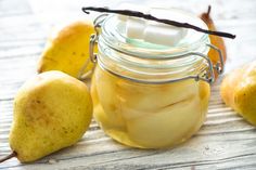 a glass jar filled with sliced pears and marshmallows on top of a wooden table