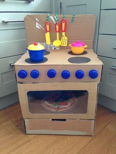 an oven made out of cardboard sitting on top of a wooden floor