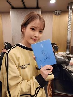 a woman holding up a blue book in front of her face and smiling at the camera