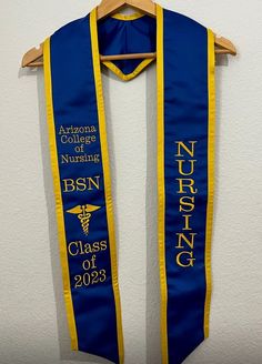 a blue and yellow nursing scarf hanging from a coat hanger with the words arizona college nursing, bsn, class of 2013 on it