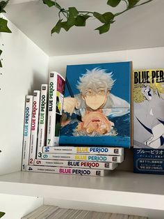 there are many books on the shelf with plants in front of them and one is blue period