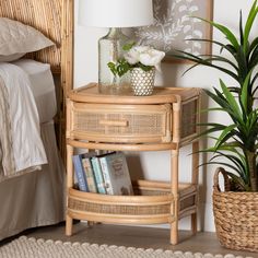 a wicker side table with books and a plant on it next to a bed