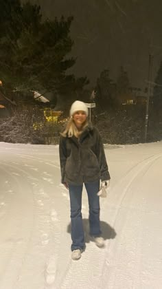 a woman standing in the snow at night