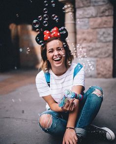 a woman sitting on the ground with soap bubbles in her hair and mickey mouse ears