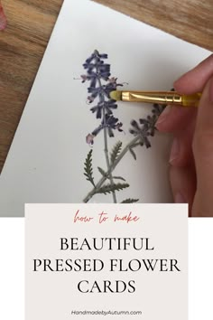 a hand holding a pen and writing on a piece of paper with the words beautiful pressed flower cards