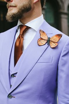 a man in a purple suit with a butterfly on his lapel