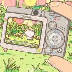 a person holding up a digital camera in front of flowers