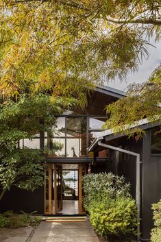 the entrance to this modern home is surrounded by greenery and trees in front of it