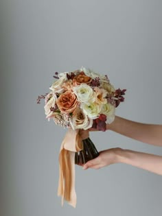 a bridal bouquet being held by two hands