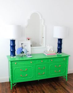 a green dresser with blue and white vases on it's top next to a mirror