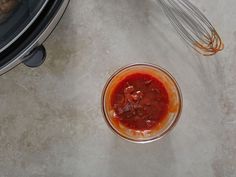 a glass bowl filled with sauce next to an electric mixer