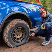 a man kneeling down next to a blue truck