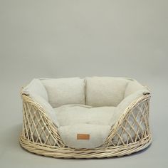 a dog bed made out of wicker with a white pillow on the top and bottom