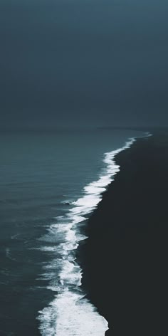 an airplane flying over the ocean on a cloudy day with dark clouds in the sky