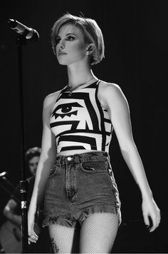 a black and white photo of a woman on stage with a microphone in her hand