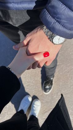 two people holding hands with red nail polish on their fingers and one person's hand in the other