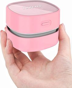 a hand holding a pink portable device in it's left palm and the top part of its body