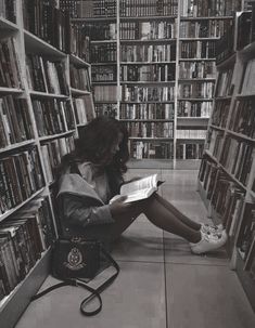 a woman sitting on the floor in front of a book shelf filled with lots of books